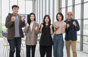 Fototapeta premium Asian business men and women look at the camera, raising their hands in joy. After brainstorming, talk about analytics, innovation, collaboration. Online business, sales techniques, strategic planning