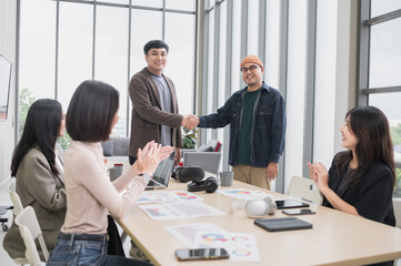 Fototapeta premium Happy Asian male businessman holding hands, looking at camera, brainstorming, talking about analysis, innovation and collaboration. Online business, sales techniques, strategic planning
