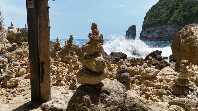 Stone cairns on a rocky beach with waves crashing. - Powered by Adobe
