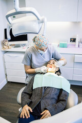 A woman is getting her teeth cleaned by a dentist