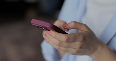 Hand of girl using smartphone in the living room at home, typing message. Close-up of young women hand.