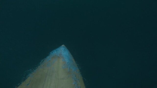 Surfer rowing on surfboard and duck dive under waves in ocean. First-person view and crashing waves