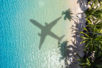 Aerial view of shadow passenger plane silhouette and sandy beach blue sea with waves at sea beach...