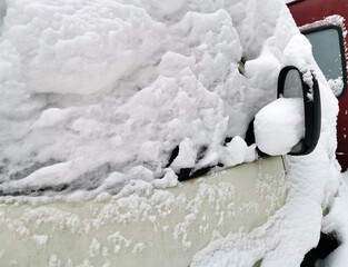 Cars covered with snow in the parking in the yard near a house