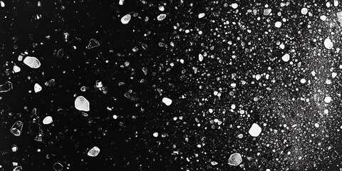 Fototapeta premium Black and white scene of a textured glass surface dotted with tiny white speckles, forming an intricate mosaic under soft light