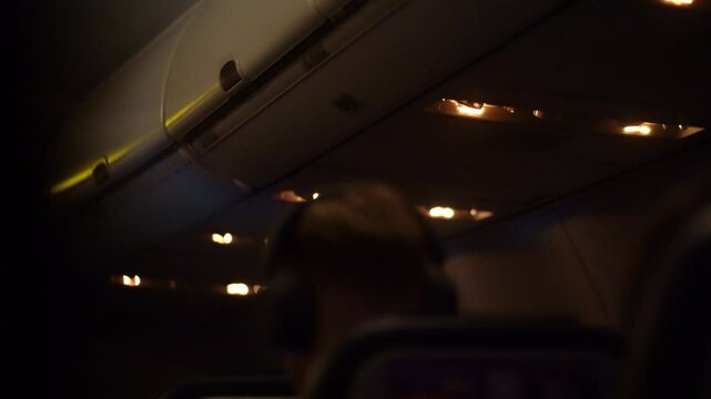 Part of the head is visible from under the seat. Artificial lighting on board the aircraft. Airplane air traffic control knobs, Reading lamps. High quality 4k footage