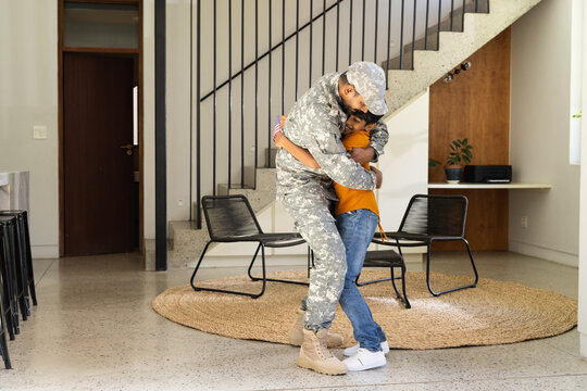 Military indian father in uniform hugging young son in homecoming embrace, copy space