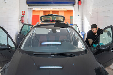 Man cleaning car interior in a workshop.