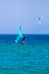 Man practicing wing foil over turquoise waters in Tarifa, under a misty blue sky heading towards the horizon.