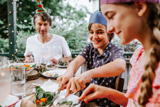 Young boy cutting food on his sisters plate