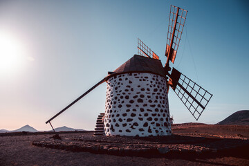View of the old, typical windmills of Villaverde, Fuerteventura, Canary Islands, with their wooden blades. almost sunset, oblique light, golden hour. Past, vintage feeling.