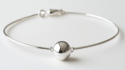 Minimalist silver bracelet with a delicate ball accent, artistically positioned on a clean white surface