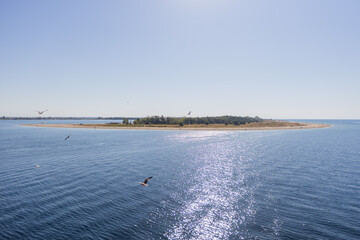 Serene view of a small island with a sandy beach, surrounded by calm turquoise waters.