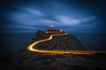 Cap de Formentor with lighthouse in Mallorca at night. Balearic islands, Mallorca, Spain. Long exposure picture with light tracks of cars.