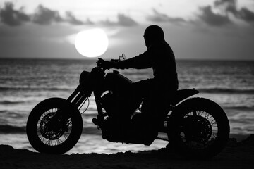 Fototapeta premium A person rides a motorcycle on the sand dunes, with a calm ocean in the background