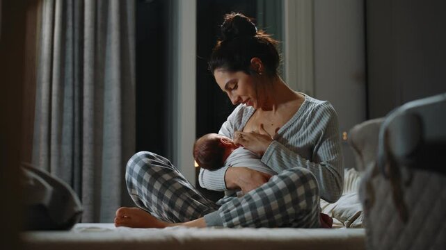 Authentic footage of a mother breastfeeding her newborn baby and drinking milk from from the mother's breast. Portrait of a Caucasian newborn baby at home. Concept of childhood and parenthood.
