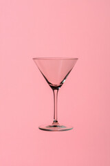 Empty martini glass standing on pink background