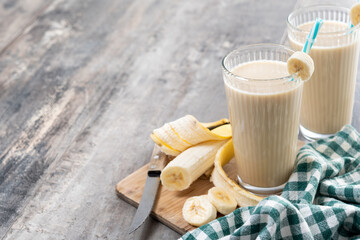 Fresh and healthy banana smoothie in glass on wooden table. Copy space