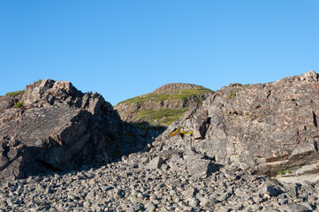 Large rocks on mountainside against blue sky. Rybachy peninsula, Murmansk region, Russia