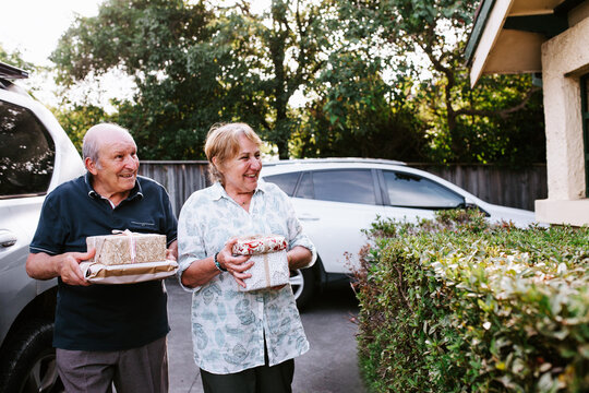 Senior couple bringing gifts walking up the driveway