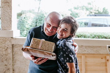 Senior man holding gifts and hugging young boy