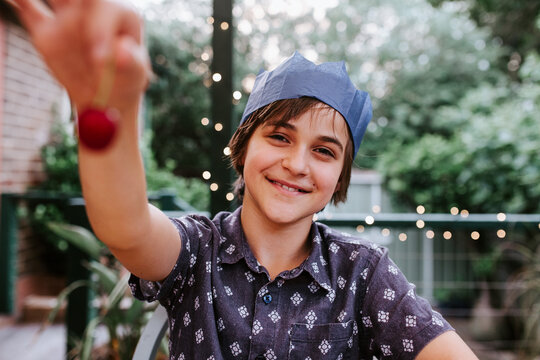 Young boy holding out a cherry smiling