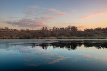 Blue hour on the lake , beautiful landscape photography on the lake with sunrise and reflactions on water , trees on the beach of the lake ,blue and orange colors.Blue sky . Water reflections 