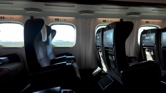 Rows of empty seats inside a green car of a Shinkansen bullet train, offering a glimpse of comfortable and modern rail travel in Japan