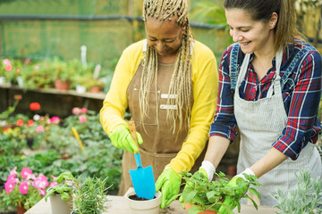 Multiracial worker women having fun working inside greenhouse garden - Spring and small business concept - Focus on right female eye