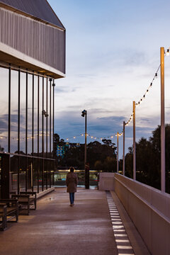 Person walking along the exterior of the Adelaide Festival Centre in the evening