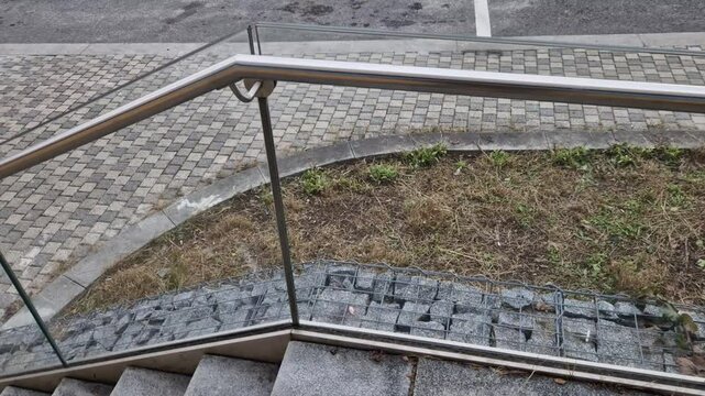 the glass railing fillings are attached to the stainless steel tubular frame with the help of screws through the glued safety glass. a flower bed with grasses in the background, roof garden terrace