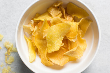 Overhead view of golden sweet potato chips in a white bowl, top view of crispy fried sweet potato chips