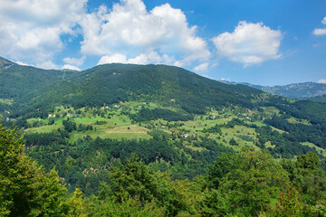 Obraz premium Lush green hills embrace a serene valley under a bright blue sky in Italy