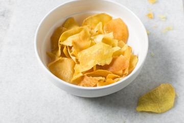 Overhead view of golden sweet potato chips in a white bowl, top view of crispy fried sweet potato chips