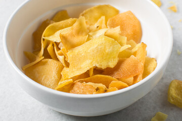 Overhead view of golden sweet potato chips in a white bowl, top view of crispy fried sweet potato chips