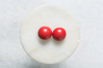 Overhead view of red earrings on marble jewelry holder, top view of vintage red earrings on a white background