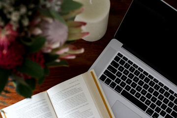 Above angle close up of corner of book and laptop keyboard on a desk