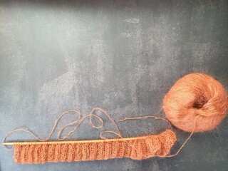 The process of knitting a jumper or sweater made of pink mohair yarn with wooden knitting needles