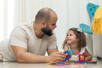 pai olhando para filha, brincando na sala