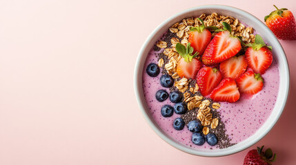 A smoothie bowl topped with granola, chia seeds, strawberries, and blueberries, served in a minimalist bowl.