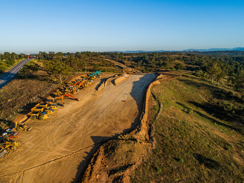 Machinery on worksite lined up in morning light ready to continue construction on bypass road
