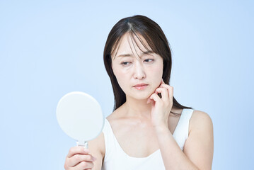 疲れた表情でスキンケアをするミドル世代の女性