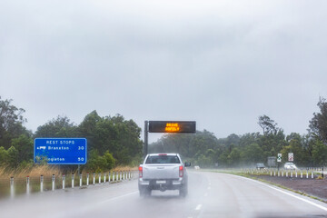 Cars traveling on slippery road with digital sign warning of hazardous driving conditions
