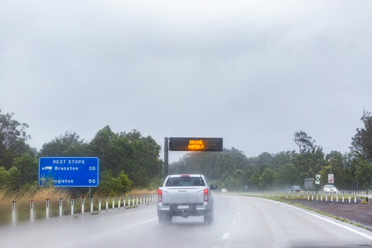 Cars traveling on slippery road with digital sign warning of hazardous driving conditions