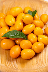 Kumquats with leaves resting on a wooden plate