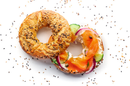 Lox bagel. A sandwich with smoked salmon and fresh vegetables on a white background, overhead flat lay shot with sesame seeds
