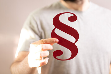 Image of a man's hand holding a red paragraph symbol. Perfect for legal, law, or writing concepts.