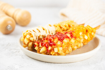 Corn dog made from skewered sausages coated in a thick layer of cornmeal and deep fried on a table. Korean street food, junk food.