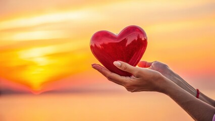 Fototapeta premium a red heart on the palm of your hand at sunset
