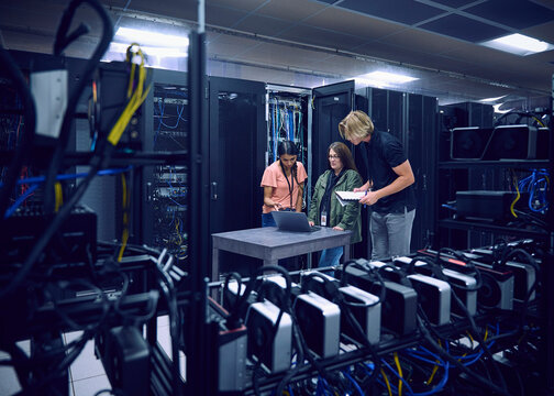 Group of technicians using laptop in server room&nbsp;